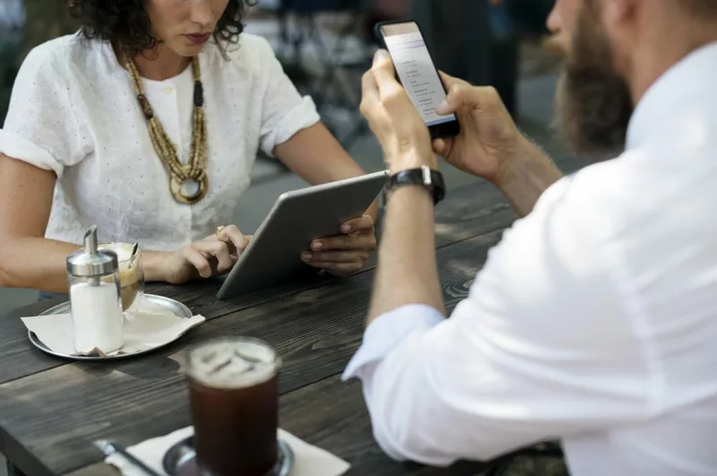 man on phone and woman on laptop at a cafe