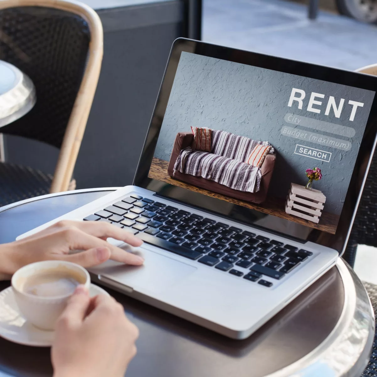 An individual using a laptop while enjoying a cup of coffee to enhance their website experience and multifamily lead nurture