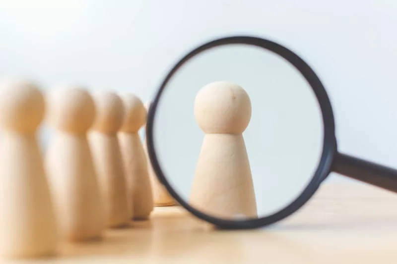 magnifying glass looking at wooden figures