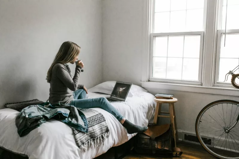 woman sitting on bead looking at laptop