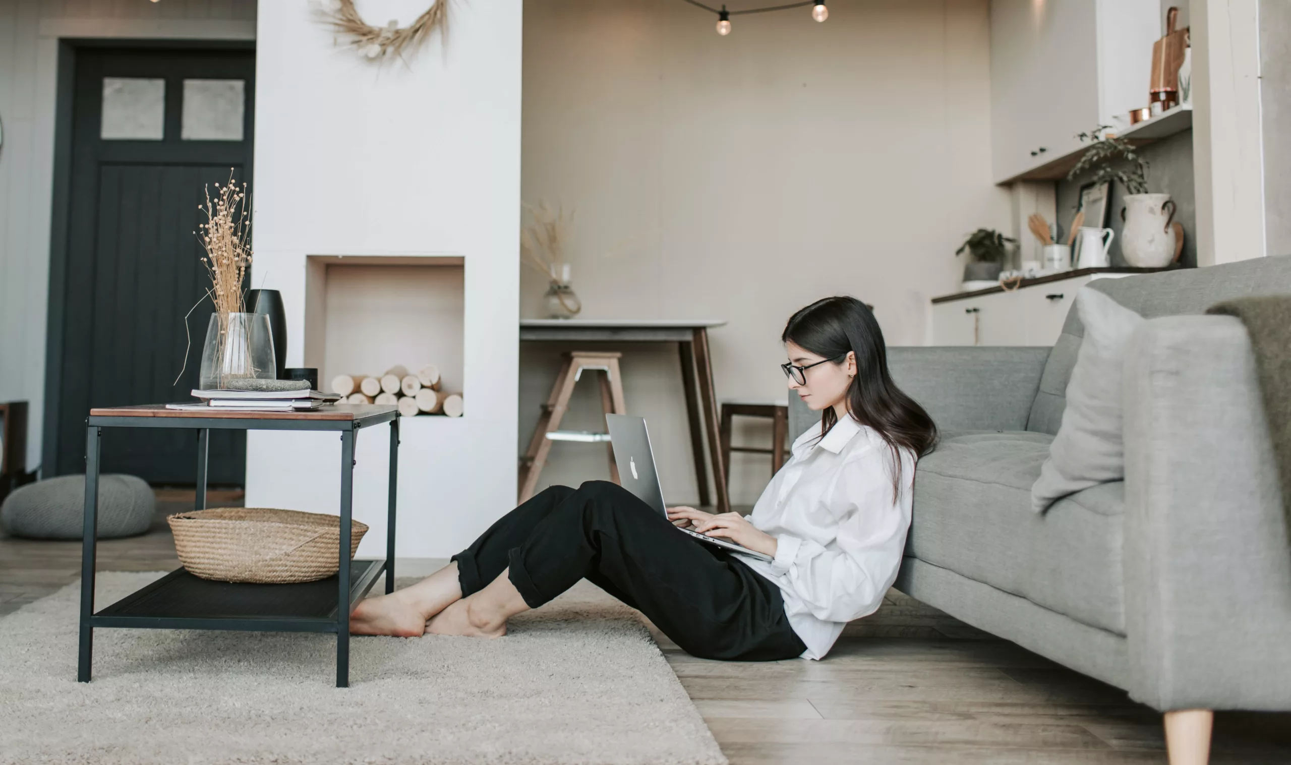 woman sitting on floor against couch with laptop