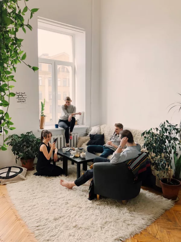four young adults gathered in a living room and talking over coffee