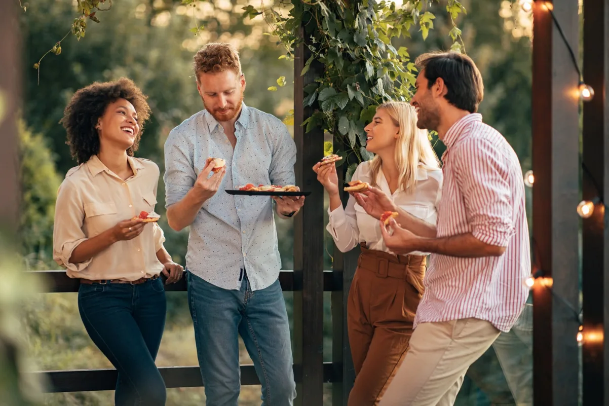 Four people laughing and eating represent how 'Outreach' is one of the best multifamily marketing ideas.