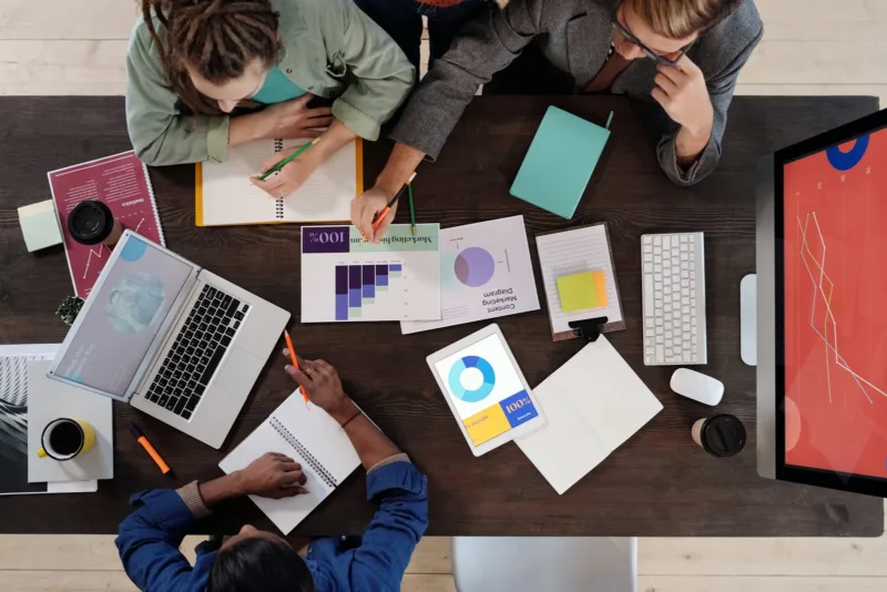 birds eye view of a table with business reports and people discussing.