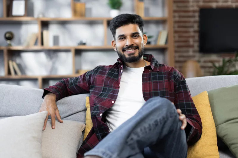 a young person sitting and smiling on a couch after having gone through an elevated renter's journey
