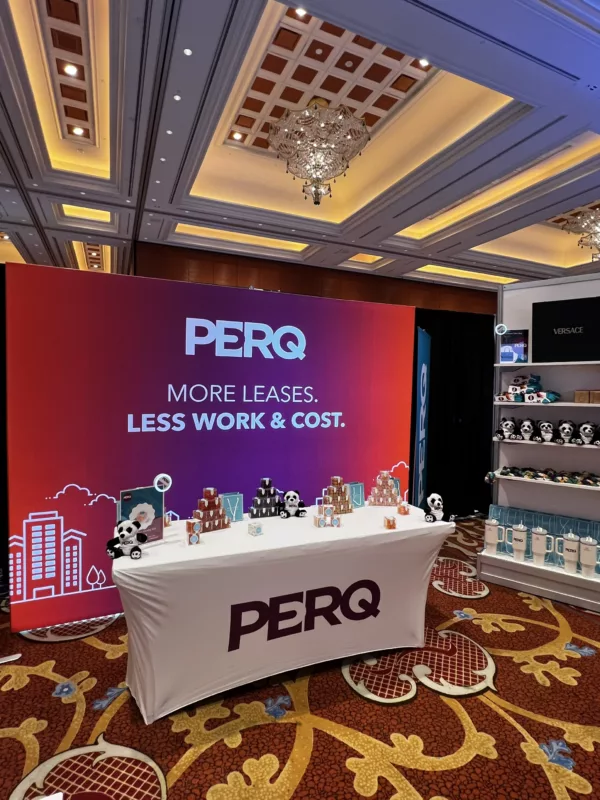 PERQ booth with a table and background banner set up at a conference