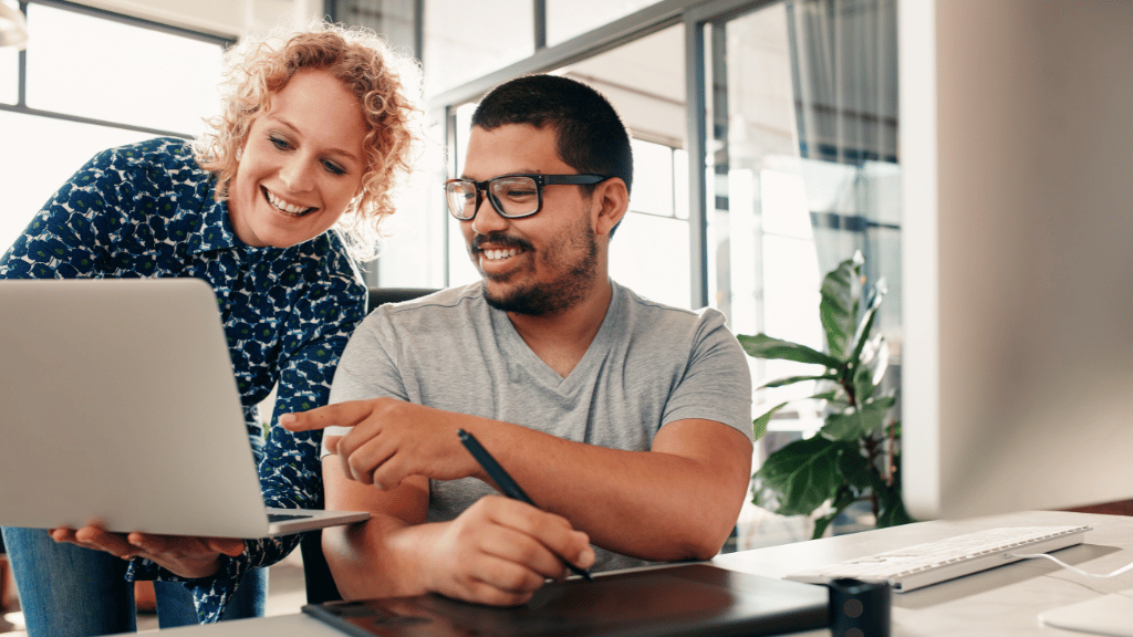 Two people looking at a laptop that one of them is holding