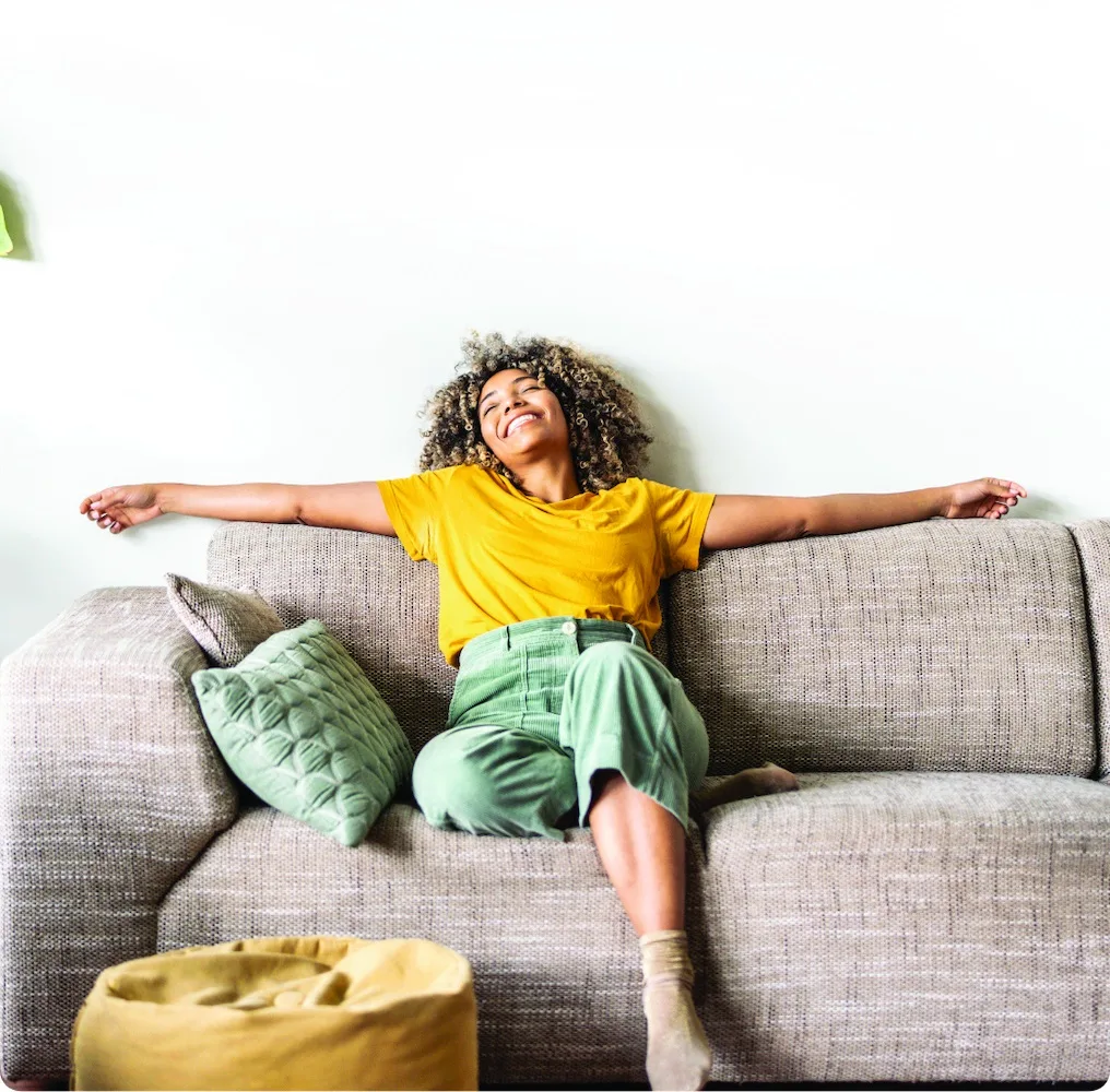 Lead Conversion Solution | PERQ AI Leasing Assistant A smiling woman with her arms wide open while sitting on a couch