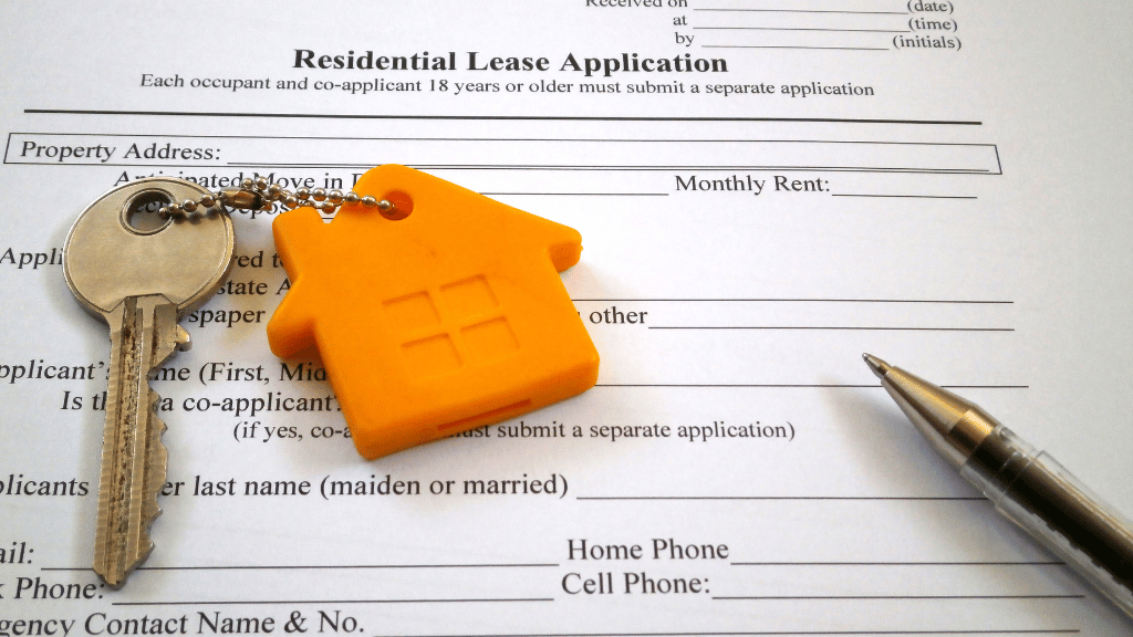 Lease-up strategy: A proven guide to maximize your property occupancy. | PERQ AI Leasing Assistant a key attached to a house-shaped keychain, sitting on top of a residential lease application