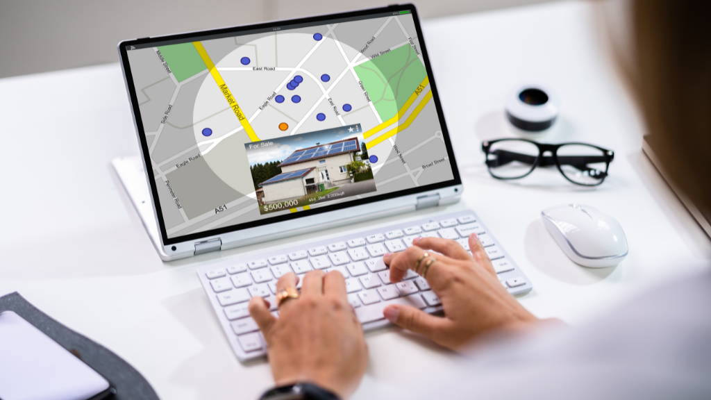hands typing on a laptop with geographical apartment search results showing on the screen